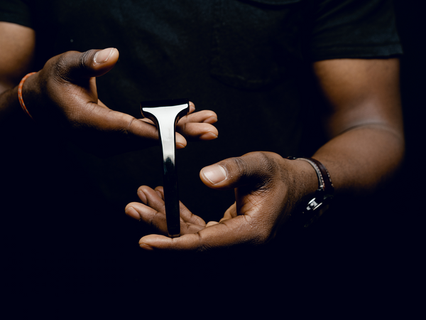 Person holding a SE Razor between their hands against a dark background