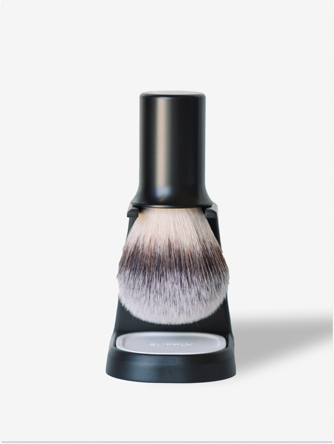 A black shaving brush on a stand with soft bristles.