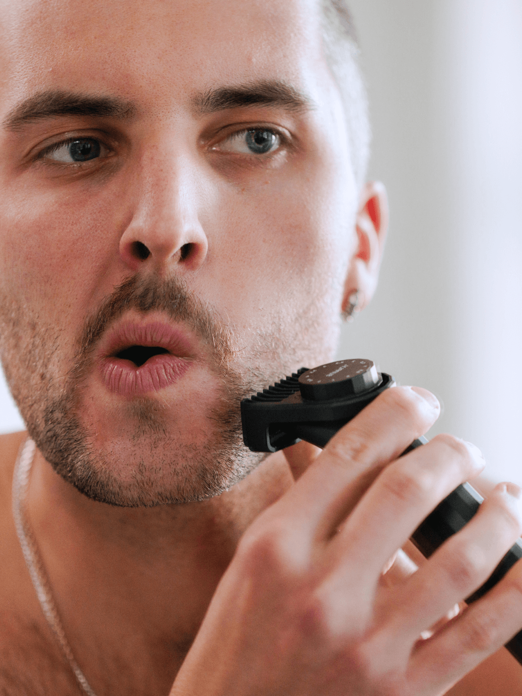 Lifestyle image of a man shaving with the supply trimmer with the guard on it. 