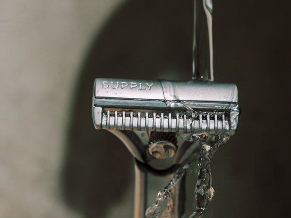 Close-up of a razor blade with 'SUPPLY' branding against a blurred background.