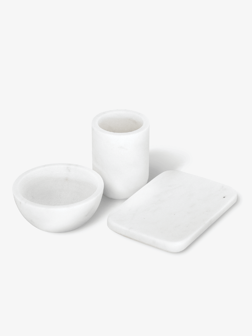 White marble bathroom accessories: soap dish, cup, and bowl.